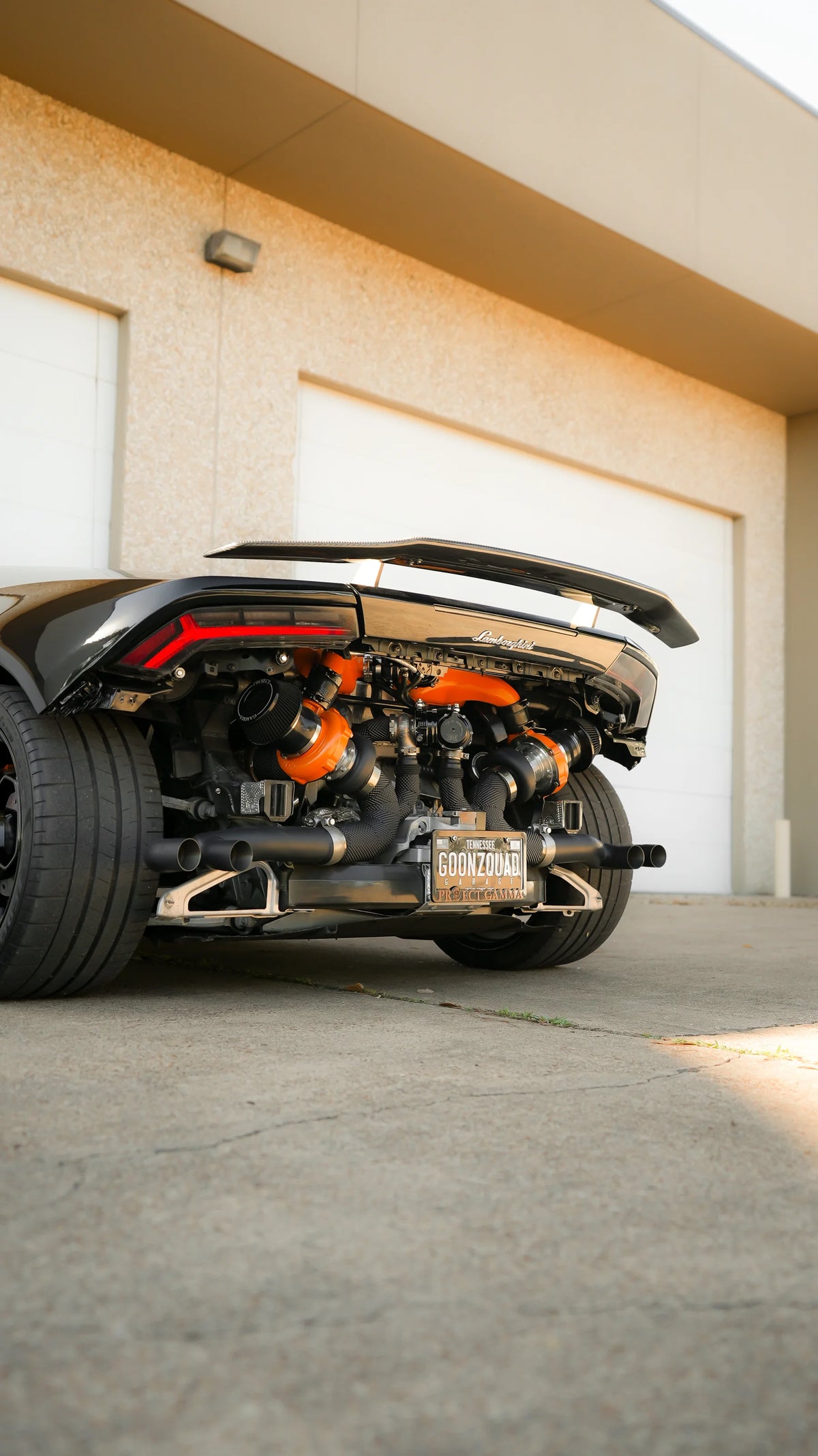 Rear of a black Lamborghini Huracan with bumper removed showing a twin-turbo engine